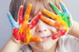 Foto di un bambino con le mani colorate di tutti i colori davanti agli occhi