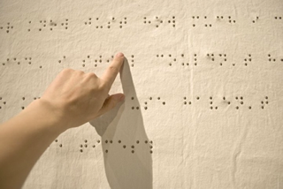 immagine di una mano che legge la scrittura Braille