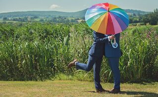 Coppia omosessuale sotto un ombrello rainbow