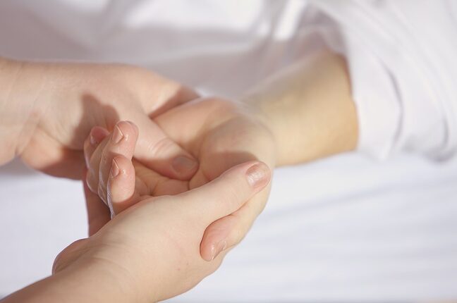 le mani di due persone strette le une nelle altre, simbolo della cura