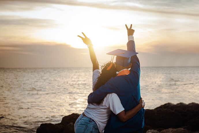 Immagine: Due ragazzi di spalle al tramonto che festeggiano la laurea