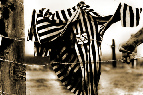 Foto d'epoca raffigurante giacca di prigioniero, a righe bianche e nere e con stella di David, appesa al filo spinato del campo di prigionia