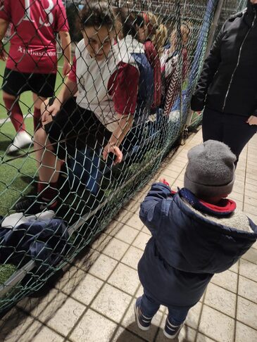 L'immagine ritrae una delle mamme a cui è stata fatta l'intervista, seduta su una panchina del campo di calcio, con il suo bambino