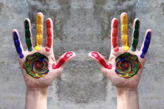 due mani dipinte con colori rainbow