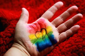 Mano con cuore disegnato e sfondo rainbow